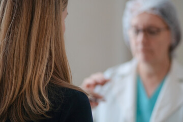 Fototapeta premium An experienced nurse in white medical uniform offers prescribed medicine to a female patient from behind in a hospital. Focus on treatment, care, and health responsibility.