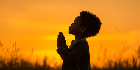 Silhouette of a Child Praying at Sunset with Hands Clasped