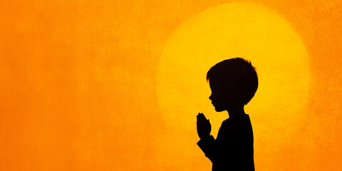 Silhouette of a Child Praying Towards a Bright Sunset Background