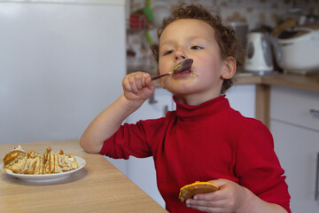 A curly child eats sitting at the home table