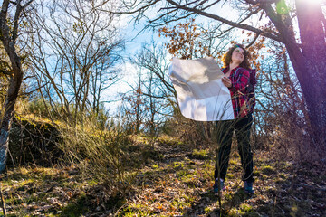 Hiker using map while exploring forest trail on sunny day