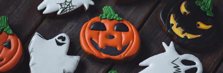 Banner. Assortment of Halloween gingerbread cookies with spiders, ghosts, jack-o-lantern on dark wooden background. Delicious homemade treat for kid's holiday party, sweet gourmet snack