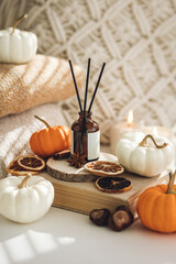 Home comfort, coziness, aromatherapy. Cozy interior with knitting, burning candles and aroma perfume diffuser in the living room. Pumpkin spicy sweet pie fall fragrance, autumn scent, relaxation