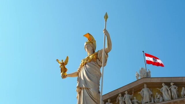 Majestic pallas athena statue, holding nike and a spear, stands proudly on the austrian parliament building roof, with the austrian flag waving gently in the background, against a clear blue sky