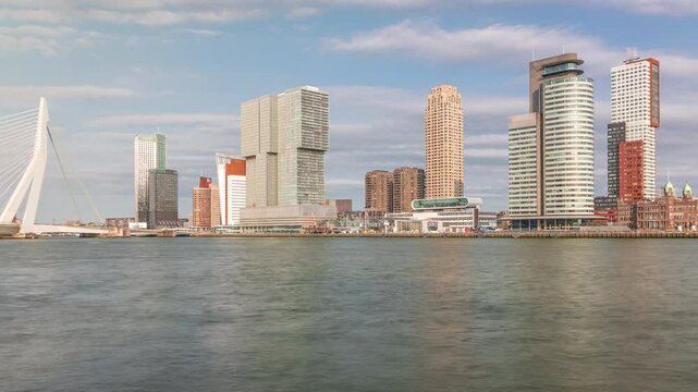 Panorama showing Rotterdam skyline timelapse from Nieuwe Maas River bank to Wilhelminapier and Kop van Zuid. Modern skyscrapers, ship terminal and Erasmus Bridge, waterfront with boats passing by