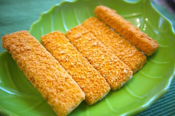 Frozen fish finger on green plate close up