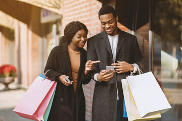 Mobile application for purchases, online order and cashback. Smiling young african american couple...