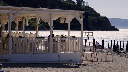People enjoying lunch at a white wooden gazebo on the beach in Scilla, Calabria, Southern Italy