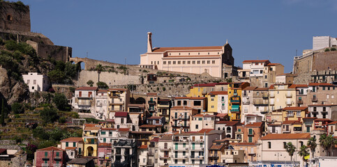 Fototapeta premium Colorful houses climbing the hill in Scilla, Calabria, towards the Sanctuary of Madonna di Reggio, with the Ruffo Castle on top