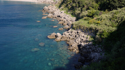 Breathtaking view of the rocky coastline meeting the turquoise waters of the Mediterranean Sea near Scilla, a charming town in Calabria, Southern Italy