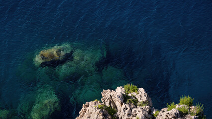 Transparent turquoise water gently caressing the rocks of the Scilla coastline, a picturesque scenery in Calabria, Southern Italy