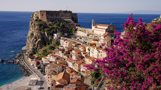 Blooming bougainvillea overlooking the Tyrrhenian Sea and the colorful houses of the village of Scilla with the Ruffo Castle in Calabria, Southern Italy