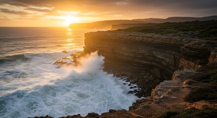 Obraz premium Dramatic Coastal Sunset Waves Crashing Against Rugged Cliffs