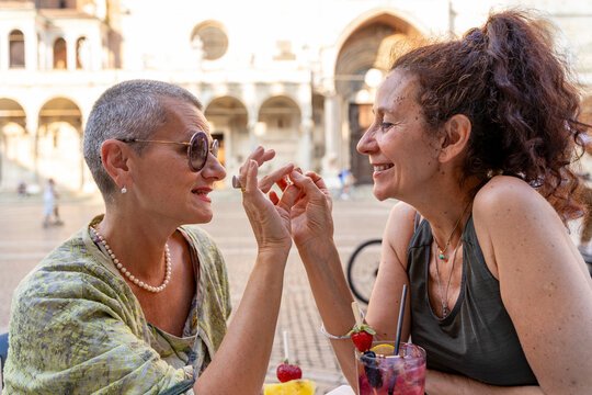 beautiful middle-aged lesbian couple making love sitting at an outdoor cafe table in a historic square