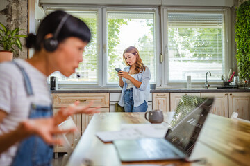 caucasian woman stand in the kitchen and use mobile phone