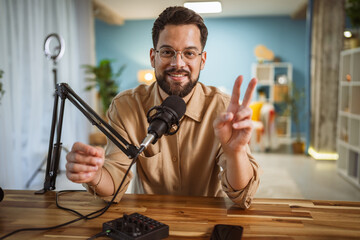 Adult man with eyeglasses and headphones smile while record a podcast