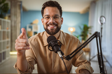 Adult man with eyeglasses and headphones smile while record a podcast