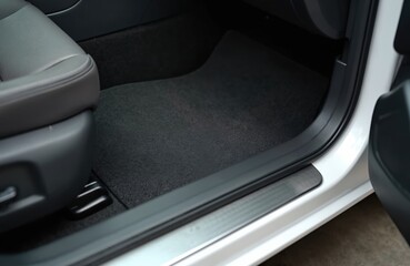 Clean car floor mats of black carpet under passenger. Auto detailing workshop. Interior of modern sedan, auto service. Dry cleaning process before sale.