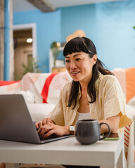 Japanese woman freelancer work from home use laptop in living room