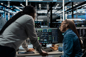 Data center manager supervising work done by engineer using artificial intelligence neural networks. Supervisor overseeing worker in server room using AI programming language to configure hardware
