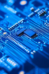 Close up of a blue circuit board with chips and intricate connecting lines