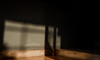 Vibrant golden light casts sharp geometric shadows on a dark wall and tiled floor.