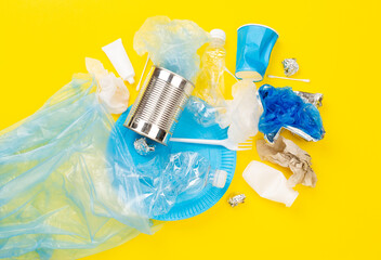 Bag with unsorted waste on color background, top view