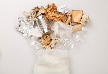 Bag with unsorted waste on color background, top view