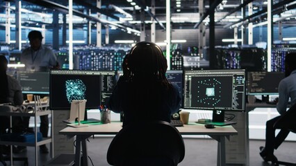 Data center engineer using algorithms to analyze large datasets, putting on headphones. Server farm...
