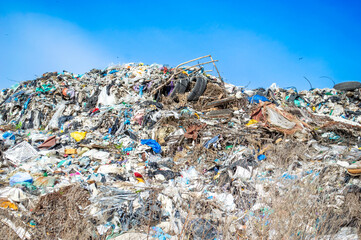 A large accumulation of trash and debris stretches across the landscape, with various materials visible against a bright sky