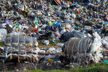 Overflowing landfill site is visible under bright sunlight with heaps of trash scattered across the...
