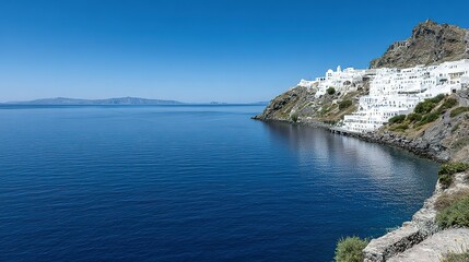 White buildings nestled on a hillside overlooking a calm sea.