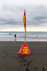 Swimmers and surfers stay safe by swimming between the flags on a beach in New Zealand, marked by...