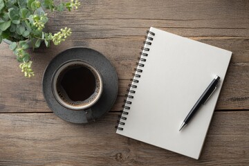 Flat lay of a cup of black coffee, a blank spiral notebook, and a black pen on a rustic wooden table.  Perfect for concepts of planning, writing, ideas, morning routine, or workspace organization. The