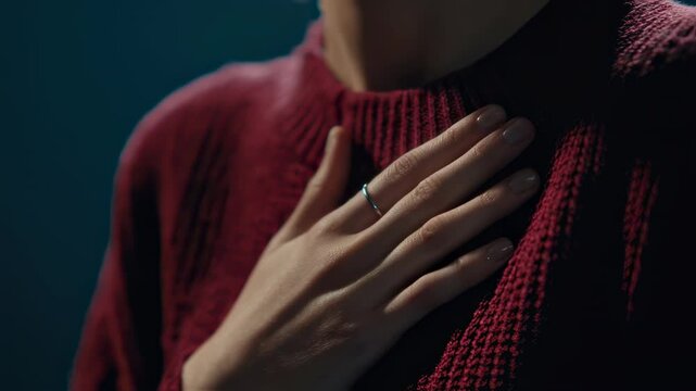 Soft skinned woman touching heart area with gentle hand, expressing deep emotional vulnerability and inner warmth against dark studio background