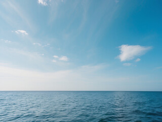 Obraz premium A serene landscape photo capturing a calm blue ocean stretching to the horizon under a vast clear sky with minimal clouds.