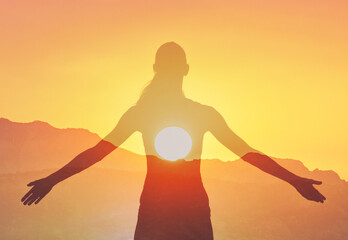 Woman enjoying the warm sunshine feeling joyful with open arms standing in a field	