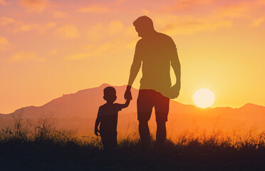 Silhouette father and his son holding hands at sunset field. Dad leading son over summer nature outdoor. Family, trust, protecting, care, parenting concept	
