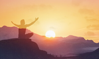 Young man facing mountain sunset rejoices, smiles looking up to the sky, enjoys life and summer, nature, happiness.