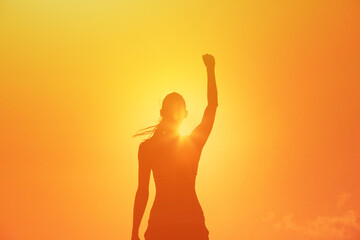 Back view of strong motivated woman celebrating workout goals towards the sun. Morning healthy training success. 
