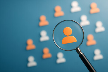 Magnifying glass focusing on orange user icon among group on blue background