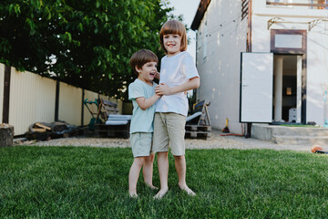 Happy children playing together outdoors in a grassy yard, showcasing friendship, joy, and carefree moments under the sun in a vibrant setting.