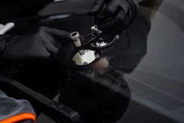 Windshield crack repair underway with a professional bridge tool and resin. Technician uses a...