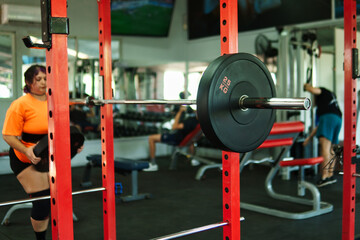 View of an overweight young Latina woman carrying weights and preparing to workout at a gym. Pushing herself. Improvement and well-being.
