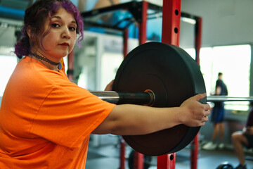 View of an overweight young Latina woman carrying weights and preparing to workout at a gym. Pushing herself. Improvement and well-being.