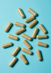 Glucomannan supplement capsules scattered on a vibrant pastel blue background, stylish flat lay composition with subtle depth of field.