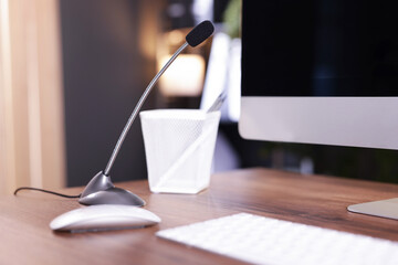 Microphone and computer on wooden desk indoors