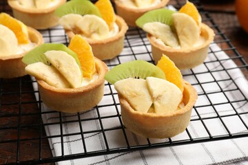Tartlets with fruits and mint on table, closeup. Delicious dessert