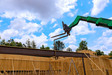 Heavy telehandler machinery lifts steel beam at construction site surrounded by wooden frames