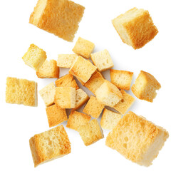 Delicious crispy croutons falling onto pile on white background, top view